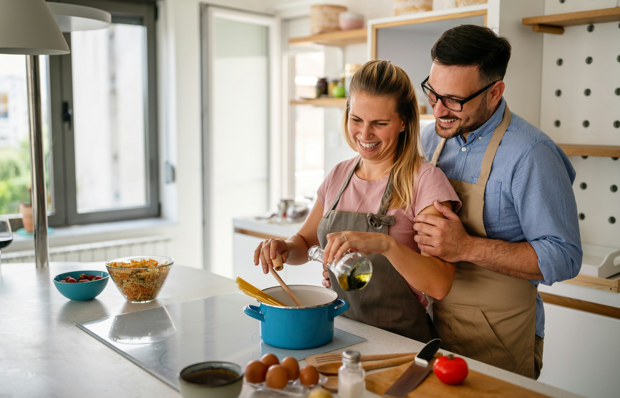 Young happy couple is enjoying and preparing healthy meal in their kitchen together